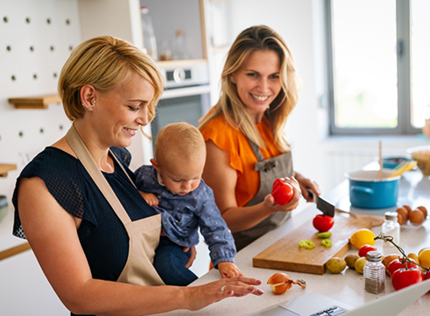 Two mom's cooking in the kitchen with their baby