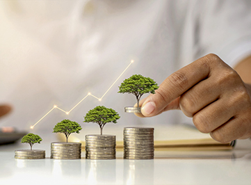 Une personne empilant des pièces de monnaie avec une plante arborescente et un graphique reflétant le concept de croissance, d’investissement, de profit et de dividende