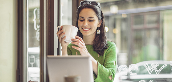 Femme savourant un café devant son ordinateur portatif